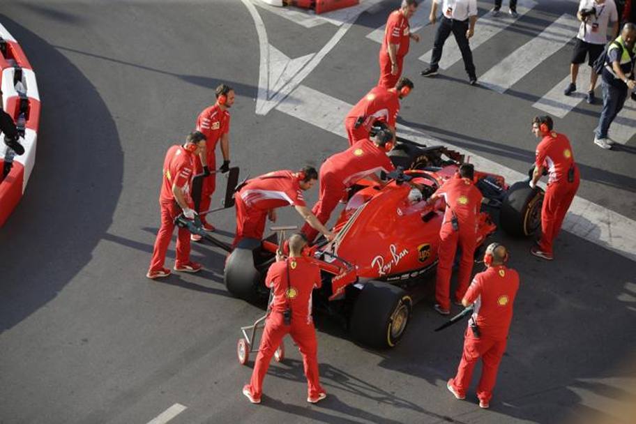 I meccanici Ferrari spingono ai box la Ferrari incidentata. Ap
